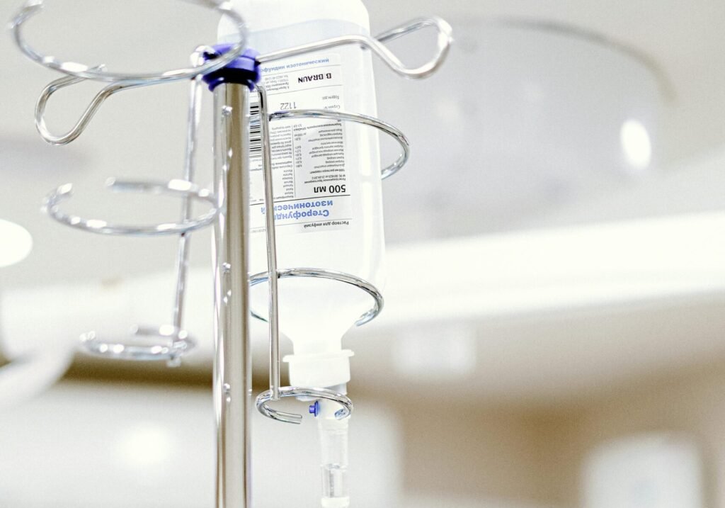 Close-up of an IV drip in a sterile hospital setting with background medical equipment.