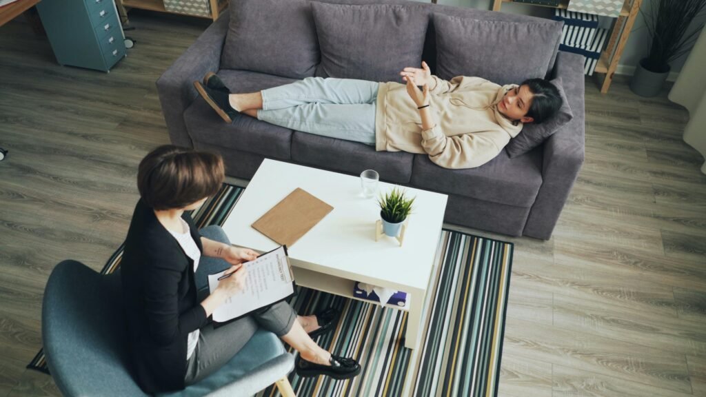 A psychotherapy session with a therapist consulting a client indoors on a sofa.