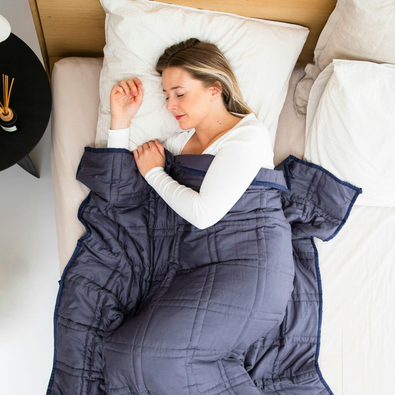 Peaceful woman sleeping with a navy weighted blanket, promoting relaxation and comfort.